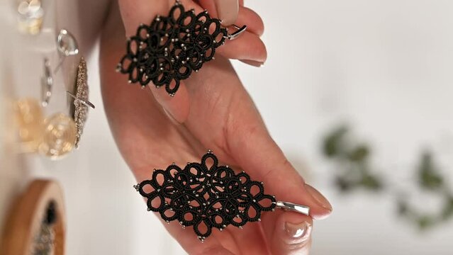 closeup hands of master holding tatted earrings jewelry. vertical banner