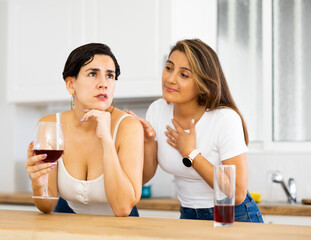 Young woman consoling the depressed woman at table in kitchen