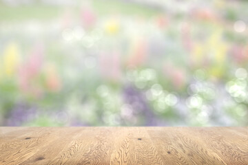 木目のある木製のテーブル越しに見えるボケた背景、奥行きのある背景、お花畑の背景画像