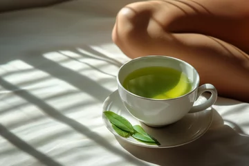 Fototapeten Bol de thé vert de luxe dans un bol en émail vert et crème à côté d'une femme assise, boisson détox et régénérante, vertus thérapeutiques du thé vert et du matcha © Leopoldine