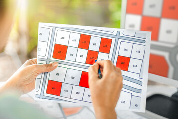 Woman holding a pencil pointing to cadastral map to decide to buy land. real estate concept with...