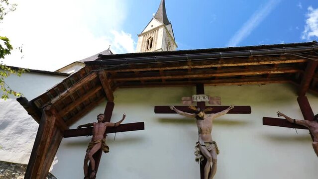 Jesus Christ and two martyrs crucifixion on wooden crosses in the Church of St. Leonard.Church of St. Leonard in Lungau, Austria. August 2023. Catholic Church architecture outside. 4k footage