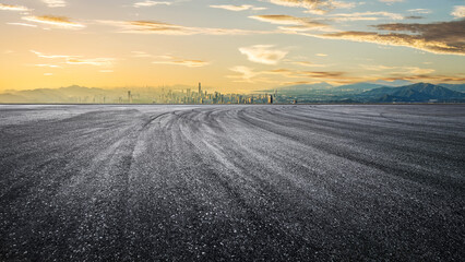 Empty asphalt road and mountains with city skyline background
