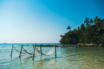 Tropical chilling out hammock in turquoise water in Thailand. Relax vacation leisure lifestyle on exotic tropical island beach, hammock hanging calm sea. Paradise beach landscape, water villas.