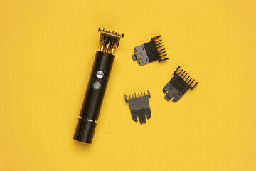 Modern cordless hair trimmer with replaceable attachments on a yellow background