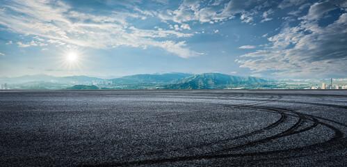 Empty asphalt road and mountains with city skyline background