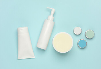 Tubes, bottles and jars of cosmetics on a blue background. Flat lay