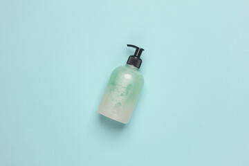 Bottle of liquid soap with dispenser on blue background