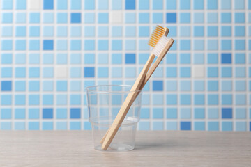 Two bamboo toothbrushes in a transparent glass in the bathroom
