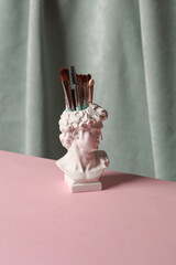 David bust vase with makeup brushes against the background of curtain. Aesthetic beauty still life. Minimalism.