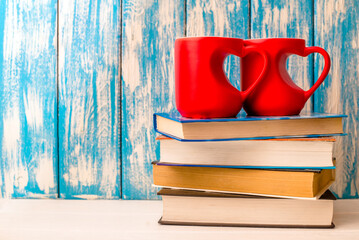two heart shaped mugs is on a stack of books
