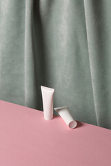 Cream tubes against the background of curtain. Aesthetic beauty still life. Minimalism.