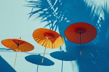 Fototapeta na wymiar Trio of Traditional Asian Paper Umbrellas Casts Elegant Shadows on Blue Background, Ideal for Cultural and Design Themes
