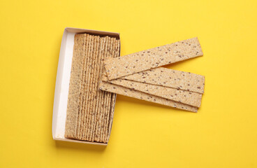 Crispy bread on yellow background. Top view
