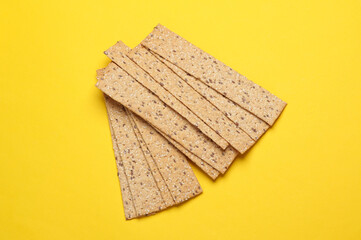 Crispy bread on yellow background. Top view