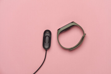 Smart bracelet with charger on pink background