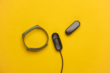 Smart bracelet with charger on yellow background