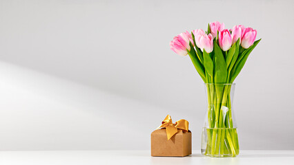 Fresh Pink Tulips Arranged in a Glass Vase Next to a Wrapped Gift Box