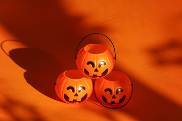 Halloween buckets on orange background with shadows
