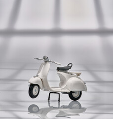 Photo of an old miniature Vespa which is also called a scooter. Photographed with a light background to isolate the white Vespa object