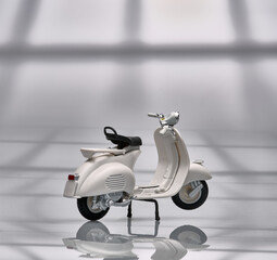Photo of an old miniature Vespa which is also called a scooter. Photographed with a light background to isolate the white Vespa object