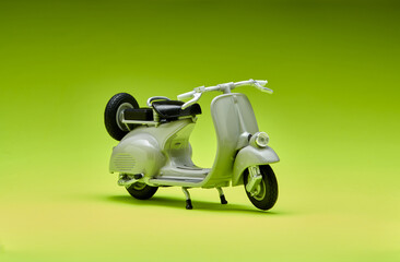 Photo of an old miniature Vespa which is also called a scooter. Photographed with a green background to isolate the gray Vespa object