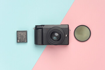 Modern mirrorless camera with accessories on a blue-pink background. Professional photographer...