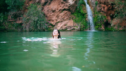 Naked woman swimming lagoon in beautiful summer nature. Lady splashing in lake