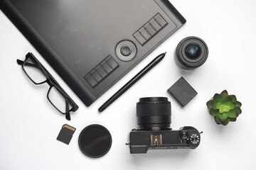 Camera, graphics tablet and photographic accessories on a white background. Equipment of a modern photographer. Top view
