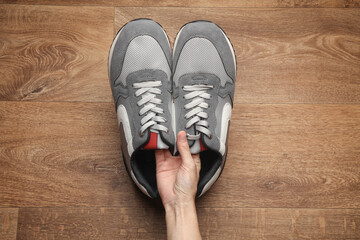 Hands holding sports sneakers on the floor. Top view