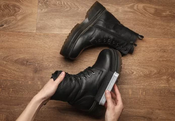 Deurstickers Hands applying shoe polish to black leather boots © splitov27