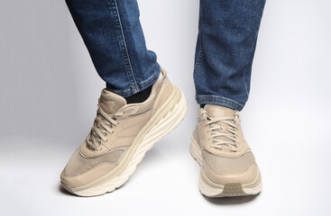 Male legs in jeans and sneakers on a white background