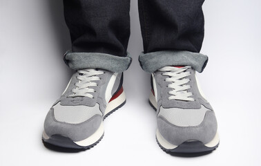 Male legs in jeans and sneakers on a white background