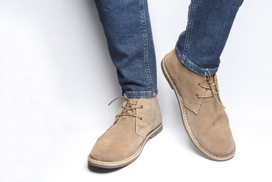 Male legs in jeans and desert shoes on a white background