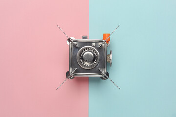 Portable camping gas burner on a blue-pink pastel background