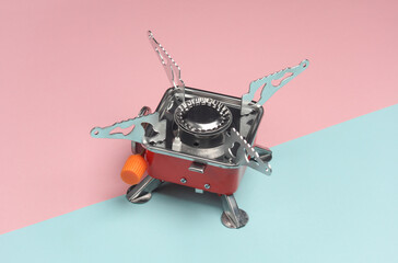 Portable camping gas burner on a blue-pink pastel background