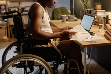 Unrecognizable african american man working with big amount of documents sitting at his desk at home