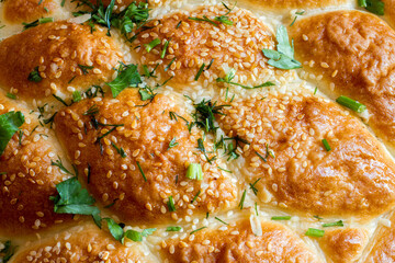 Fresh baked goods close-up. Pie with herbs and sesame seeds. Close-up of the surface of the pie.