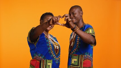 African american couple doing heart shaped sign with their hands, expressing true love and sincere...
