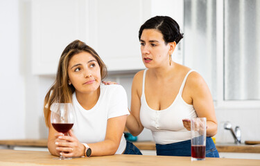 Young woman consoling the depressed woman at table in kitchen