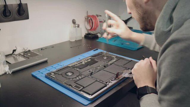 Computer Service. A man is repairing a laptop. 