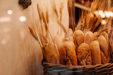 Fresh baked multigrain bread in a wicker basket with ears of wheat in a baked goods store.
