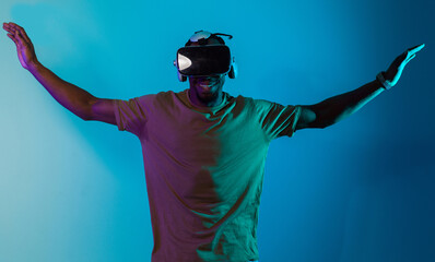 African American man dons VR glasses, engrossed in a virtual reality simulation, gesturing with...