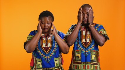 Sick ethnic people having fun symptoms on camera, suffering from migraine and tension. African american married couple rubbing temples to ease pressure and get rid of headache on camera.