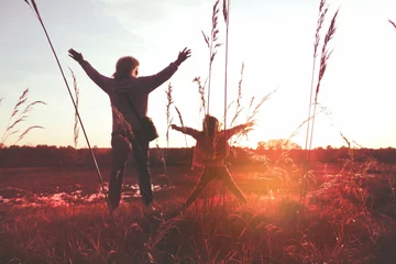 Foto auf Alu-Dibond Child girl with mother in the meadow with raised hands, rear view. Relaxing. Summer sunset. Enjoying Life © ElenaEmiliya
