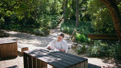 Beautiful student studying nature sitting table. Girl looking at notebook notes
