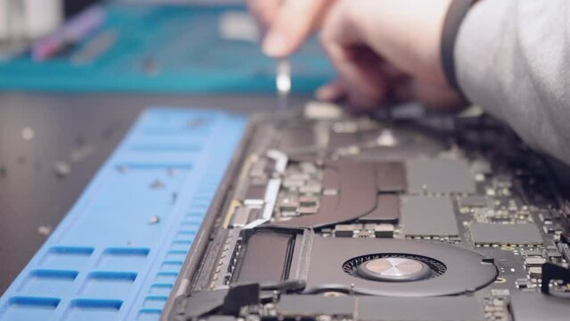Computer Service. A man is repairing a laptop. Dolly shot. Refocus