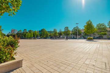 Trg Slobode or freedom square in the centre of Niksic, Montenegro on a sunny day. Flat open space in the centre of a city, surrounded by trees and foliage.