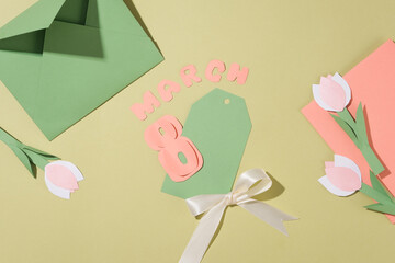 The text “March 8” cut from coral paper featured with a card a bow. Few tulip flowers made of paper displayed. Copy space for text adding. Banner or leaflet for March 8