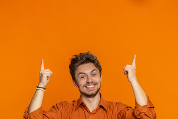 Caucasian smiling man showing thumbs up pointing overhead empty place, advertising area for...